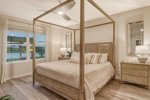 bedroom featuring a water view, ceiling fan, and light hardwood / wood-style flooring