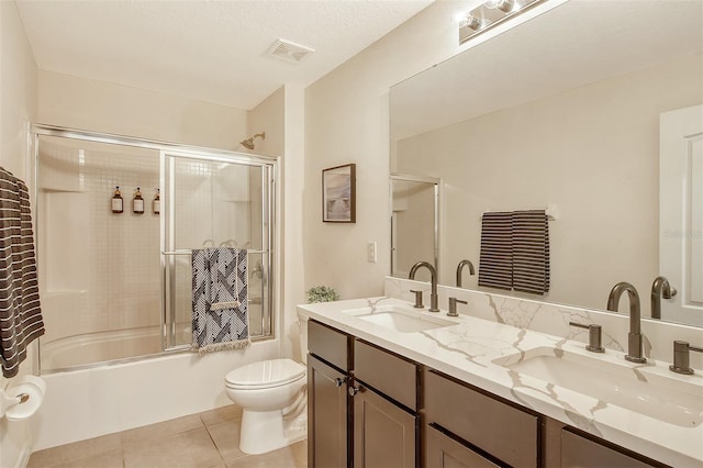 full bathroom featuring toilet, tile patterned flooring, vanity, combined bath / shower with glass door, and a textured ceiling