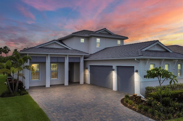 traditional home with decorative driveway, a tile roof, and an attached garage