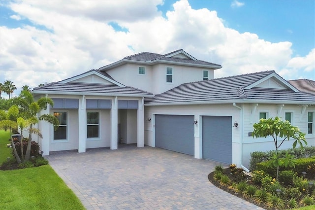 view of front of house featuring a tiled roof, decorative driveway, and an attached garage