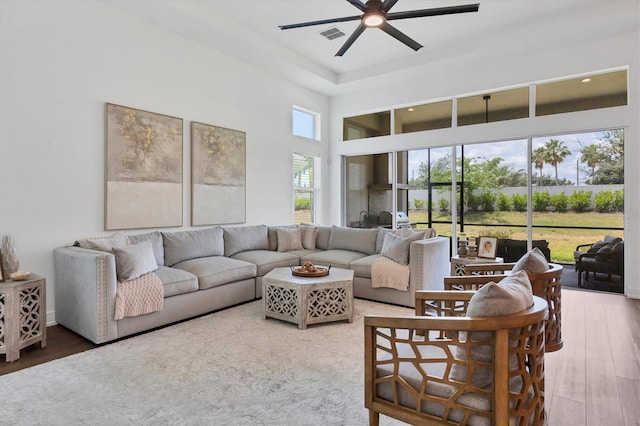 living room featuring hardwood / wood-style flooring, a towering ceiling, and ceiling fan