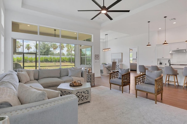 living room with light hardwood / wood-style floors, a high ceiling, and ceiling fan