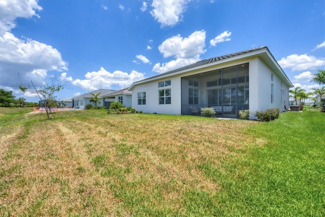 rear view of house featuring a lawn, central AC unit, and a sunroom