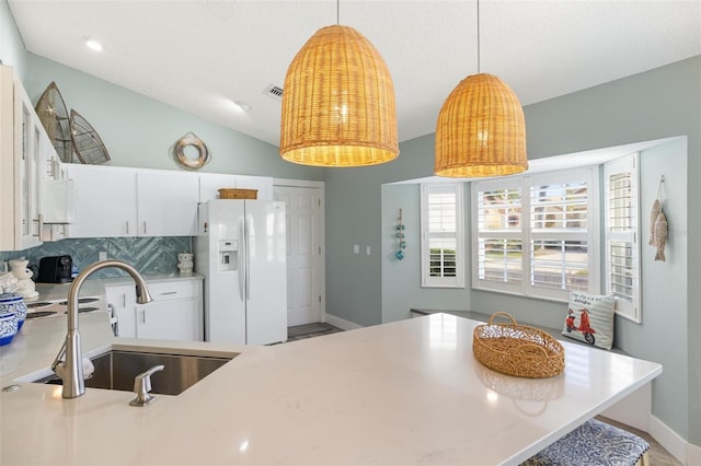 kitchen featuring tasteful backsplash, white cabinetry, vaulted ceiling, sink, and white refrigerator with ice dispenser