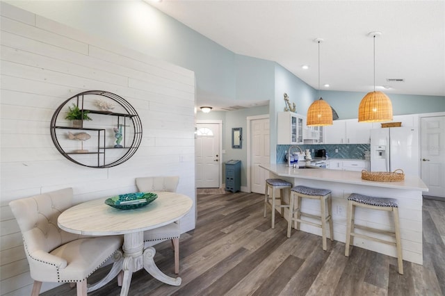 kitchen featuring kitchen peninsula, hanging light fixtures, white cabinetry, dark hardwood / wood-style floors, and white refrigerator with ice dispenser