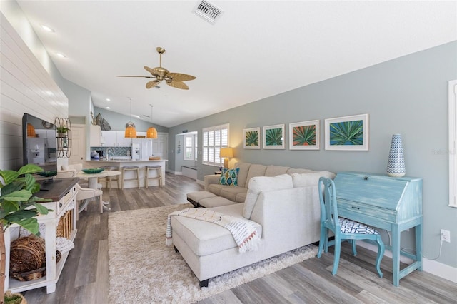 living room with ceiling fan, lofted ceiling, and light wood-type flooring