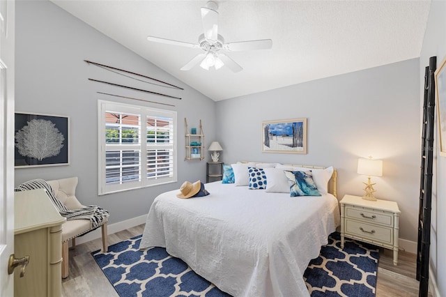 bedroom with ceiling fan, vaulted ceiling, and light hardwood / wood-style floors