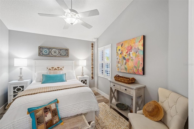 bedroom featuring vaulted ceiling, a textured ceiling, light hardwood / wood-style floors, and ceiling fan