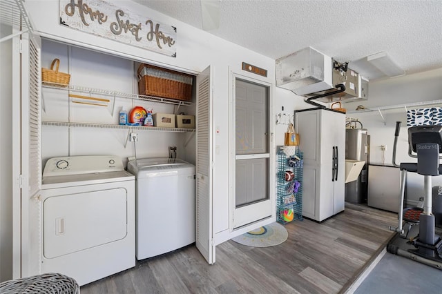 washroom featuring a textured ceiling, electric water heater, washer and dryer, and dark hardwood / wood-style floors