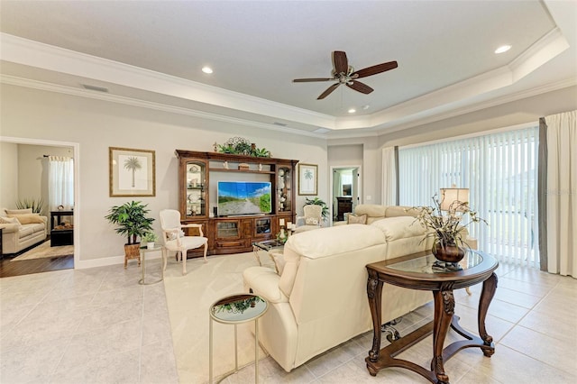 tiled living room with ceiling fan, ornamental molding, and a tray ceiling