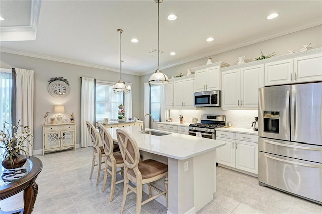 kitchen featuring appliances with stainless steel finishes, white cabinetry, a breakfast bar area, a kitchen island with sink, and light stone countertops