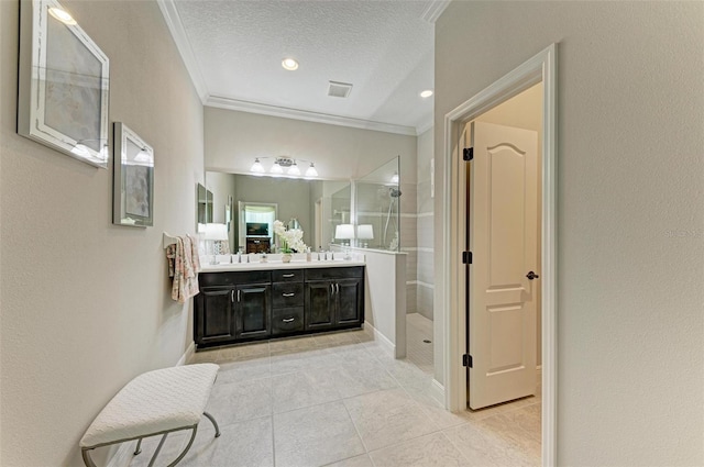 bathroom with crown molding, vanity, a textured ceiling, and a tile shower