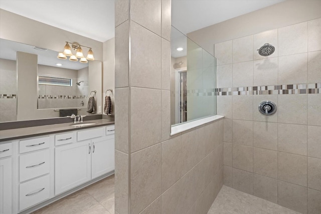 bathroom with vanity, a tile shower, and tile patterned flooring