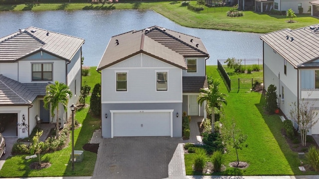 view of front of home featuring a water view, a front lawn, and a garage