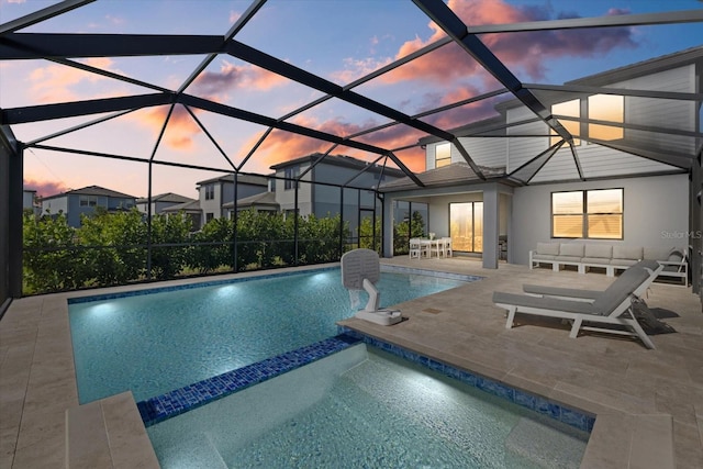 pool at dusk with a patio and glass enclosure