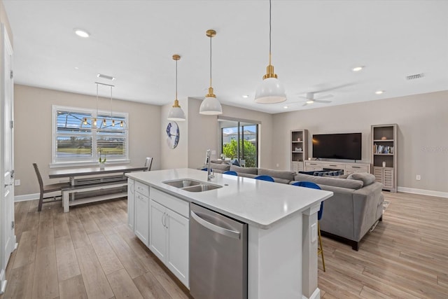 kitchen featuring white cabinetry, hanging light fixtures, stainless steel dishwasher, and sink