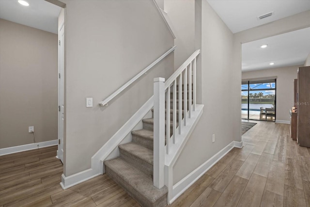 staircase with a water view and wood-type flooring