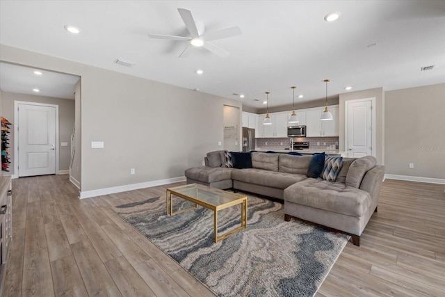 living room featuring light wood-type flooring and ceiling fan