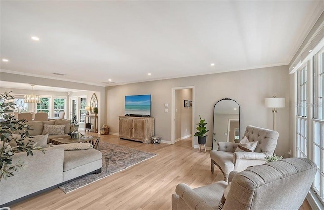 living room featuring ornamental molding, a notable chandelier, and light wood-type flooring