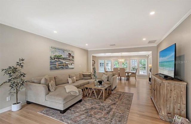 living room with crown molding, light hardwood / wood-style flooring, and a notable chandelier