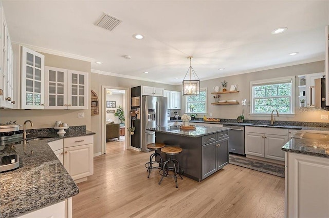 kitchen with light hardwood / wood-style floors, appliances with stainless steel finishes, a kitchen island, and white cabinets