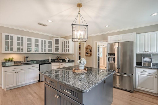 kitchen with a kitchen island, white cabinetry, light hardwood / wood-style flooring, decorative light fixtures, and stainless steel appliances