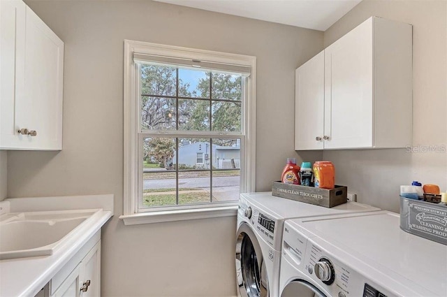 clothes washing area with sink, washer and dryer, cabinets, and plenty of natural light