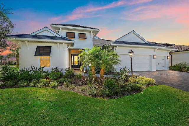 view of front of home with a garage and a lawn