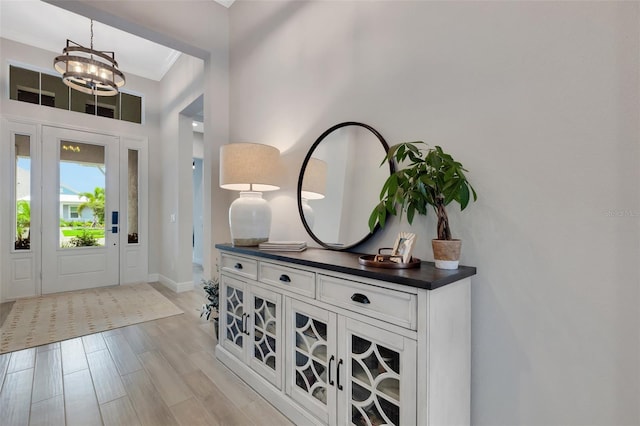 entrance foyer featuring light hardwood / wood-style floors, a notable chandelier, and ornamental molding