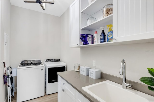 laundry room with light hardwood / wood-style flooring, cabinets, sink, and separate washer and dryer