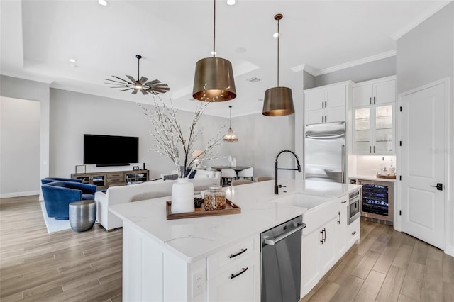 kitchen with a kitchen island with sink, hanging light fixtures, stainless steel appliances, white cabinetry, and light stone counters