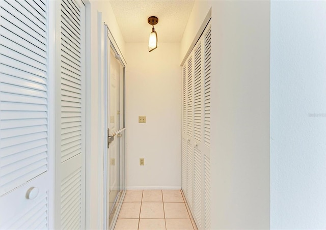 hallway featuring a textured ceiling and light tile patterned floors