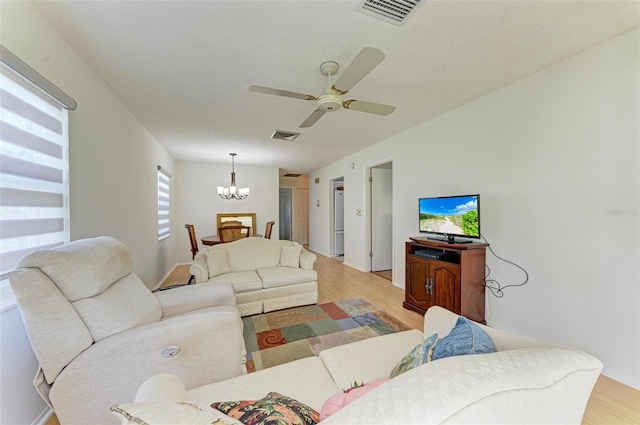 living room with light hardwood / wood-style floors, a textured ceiling, and ceiling fan with notable chandelier