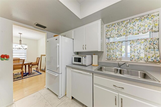 kitchen featuring hanging light fixtures, sink, light wood-type flooring, white cabinets, and white appliances