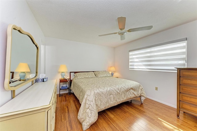 bedroom with light hardwood / wood-style floors, a textured ceiling, and ceiling fan