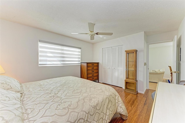 bedroom featuring light hardwood / wood-style flooring, a textured ceiling, a closet, and ceiling fan