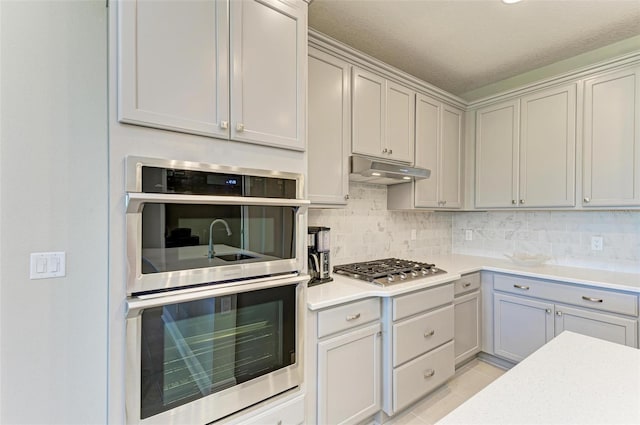 kitchen with light tile patterned floors, appliances with stainless steel finishes, a textured ceiling, and decorative backsplash