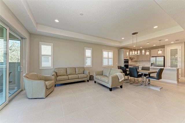 living room with a raised ceiling, a textured ceiling, and light tile patterned flooring