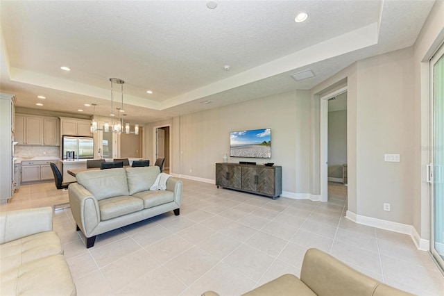 living room featuring light tile patterned flooring, a textured ceiling, and a tray ceiling