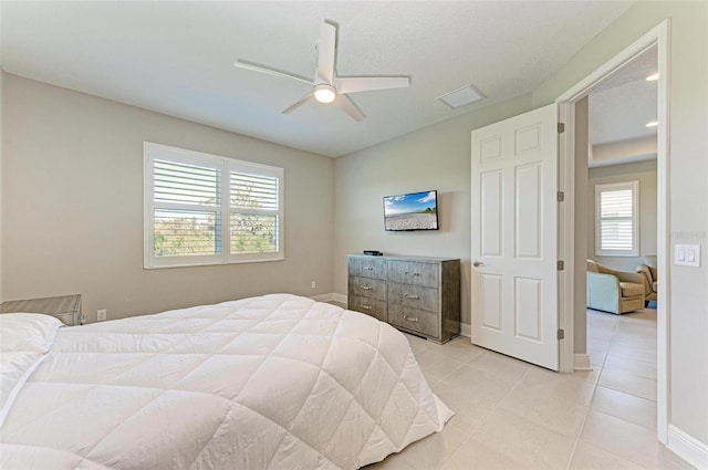 tiled bedroom featuring multiple windows and ceiling fan