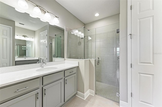 bathroom featuring vanity, an enclosed shower, a textured ceiling, and tile patterned flooring