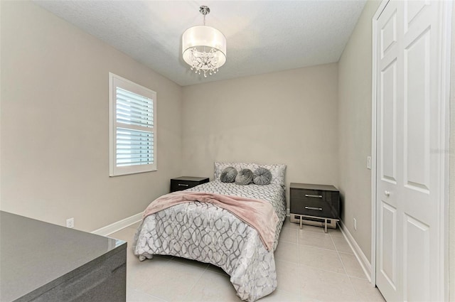 bedroom with a closet, a textured ceiling, light tile patterned floors, and a chandelier