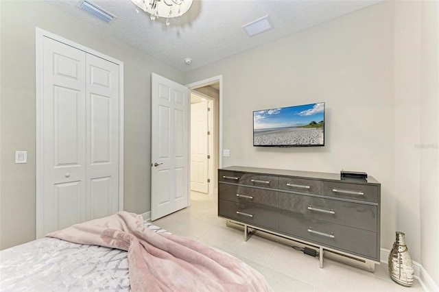 tiled bedroom with a textured ceiling and a closet