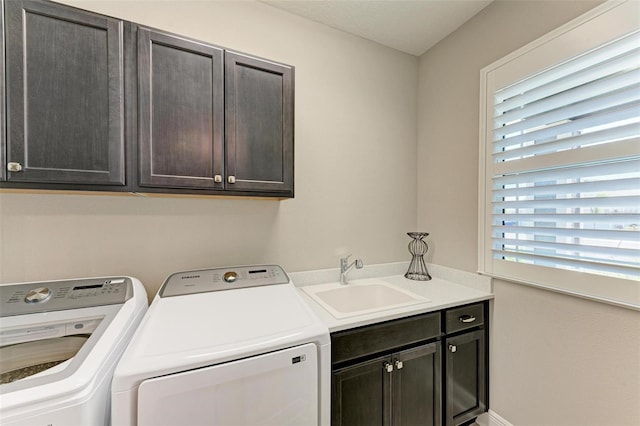 clothes washing area with sink, washer and clothes dryer, and cabinets