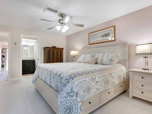 carpeted bedroom with ensuite bath, a textured ceiling, and ceiling fan