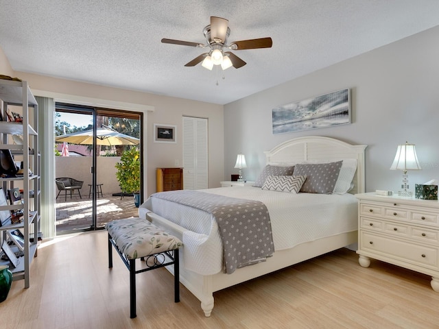 bedroom with a closet, access to outside, a textured ceiling, light hardwood / wood-style floors, and ceiling fan