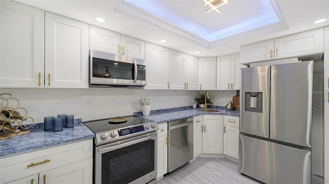 kitchen featuring sink, a raised ceiling, light stone counters, white cabinets, and appliances with stainless steel finishes