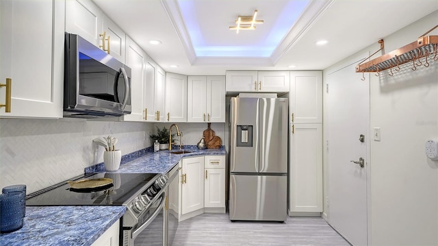 kitchen with a raised ceiling, white cabinetry, sink, and appliances with stainless steel finishes