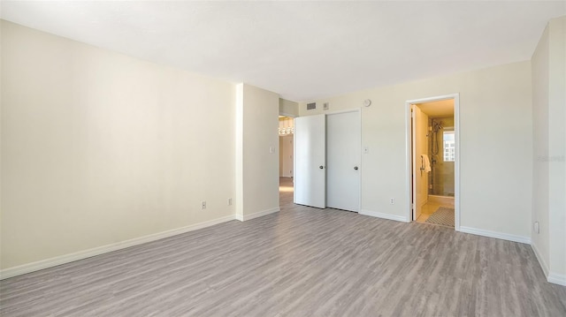 unfurnished bedroom featuring ensuite bathroom, light hardwood / wood-style floors, and a closet