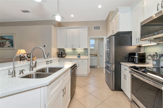 kitchen featuring white cabinets, light stone counters, stainless steel appliances, and hanging light fixtures